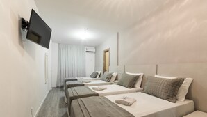 A hotel room with two single beds, a TV mounted on the wall, an air conditioning unit, and a window with curtains. - Hotel Negrini (Balneário Camboriú)
