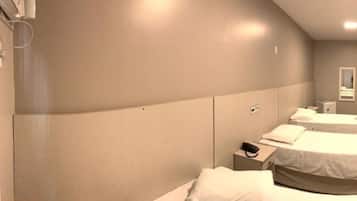 Une chambre d’hôtel avec deux lits, une table de chevet avec un téléphone et une petite armoire.
