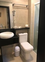 Un baño con lavamanos blanco, inodoro y zona de ducha.