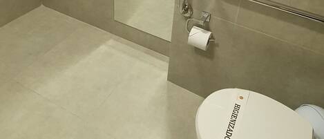 Une salle de bain équipée d’un lavabo, de toilettes, d’un sèche-cheveux et d’une barre d’appui.