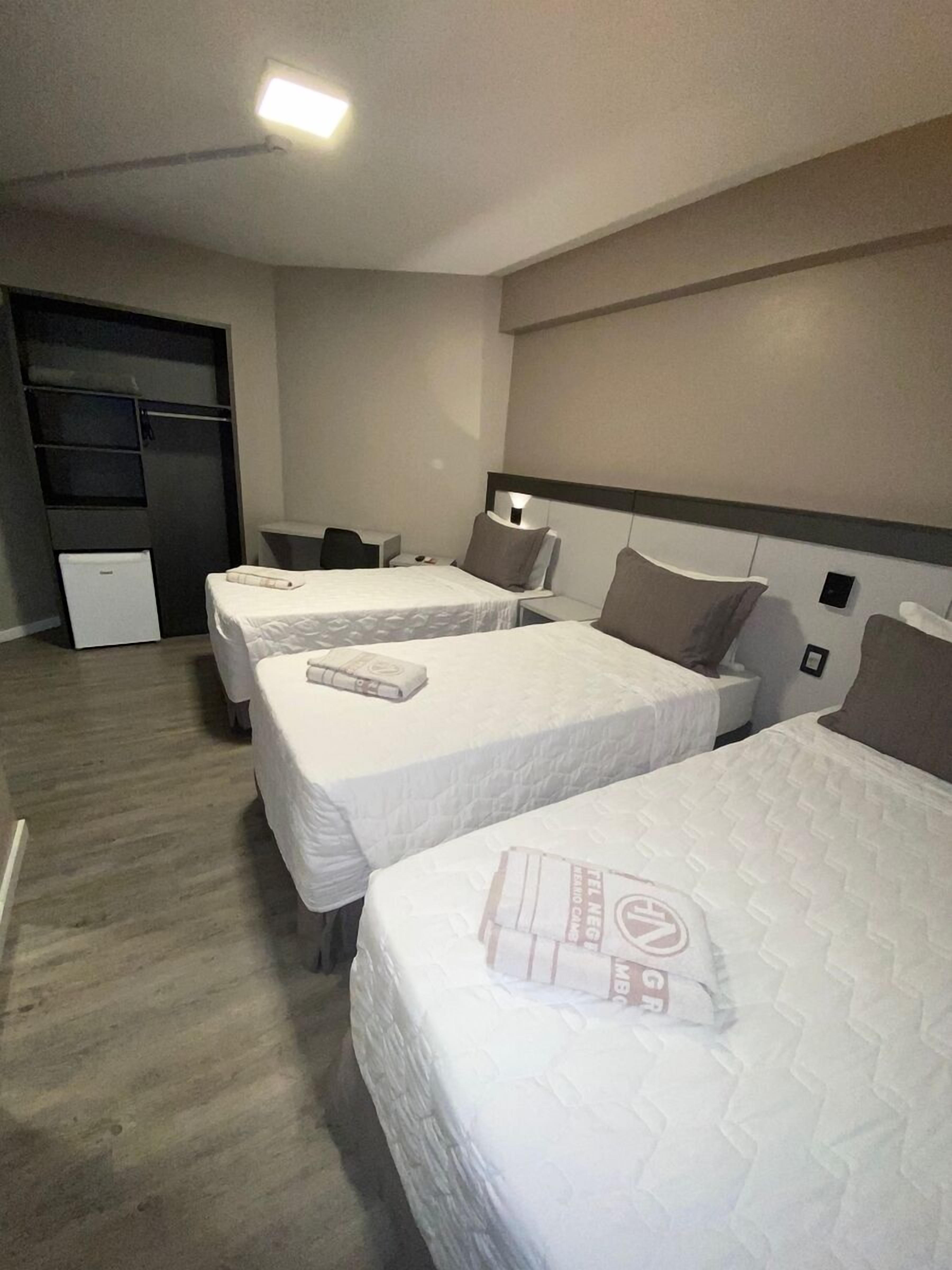 A hotel room with two beds, a small desk, and a wardrobe.