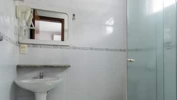Een badkamer met een douchecabine van glas, een wastafel op een zuil en een toilet.