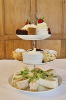 A three-tiered dessert stand with cakes, scones, and sandwiches.
