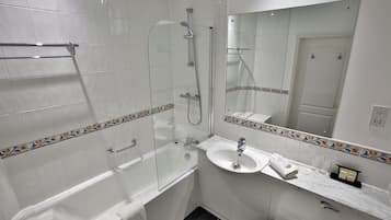 A modern bathroom with a glass-enclosed shower, a white bathtub, and a marble countertop sink.