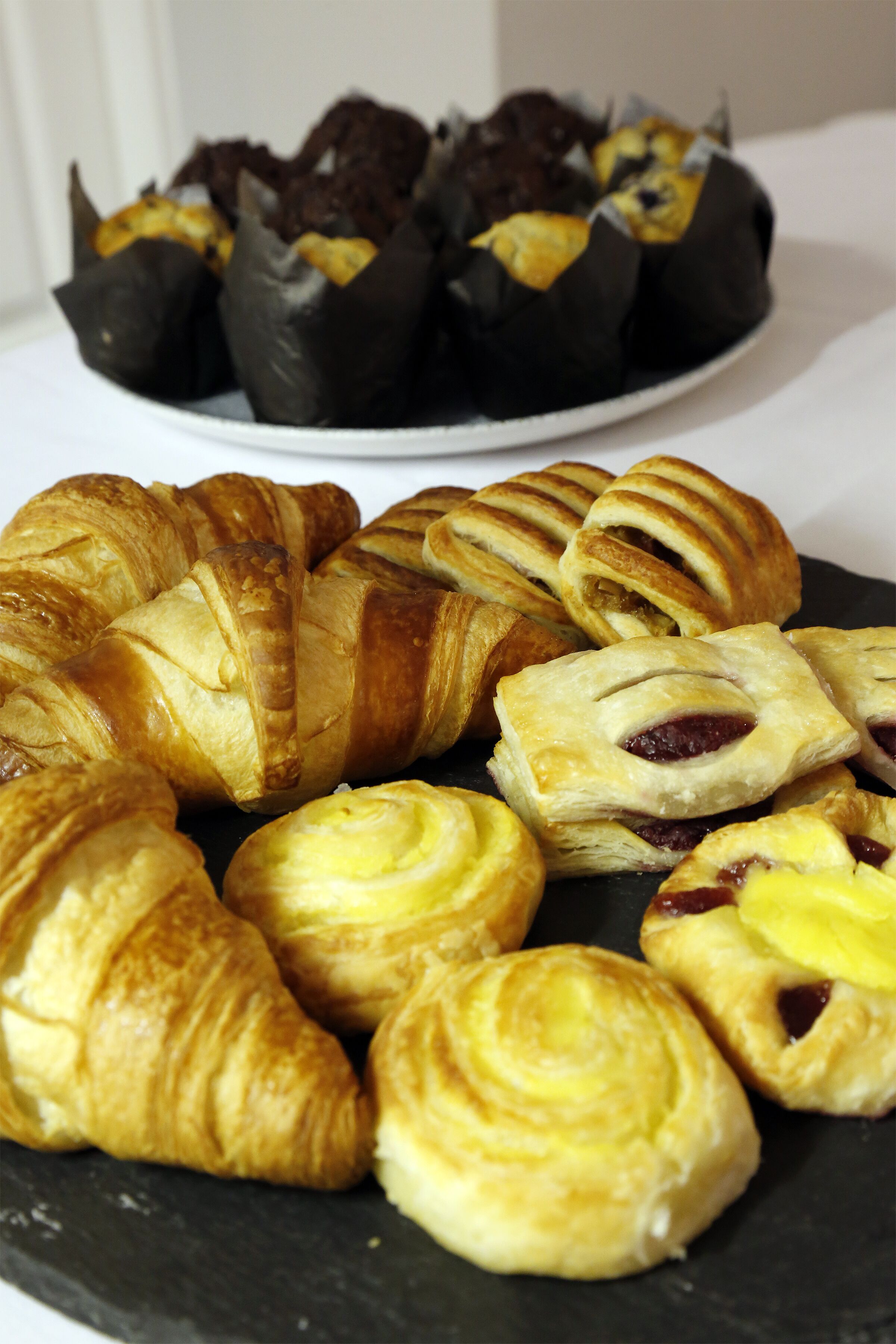Variedad de pasteles en un plato, incluyendo croissants y productos cubiertos de chocolate.