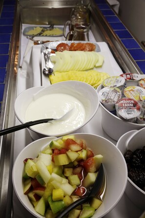A buffet with various food items including sliced fruits, yogurt, and a bowl of mixed fruit salad. - Quorn Grange Hotel (Loughborough)