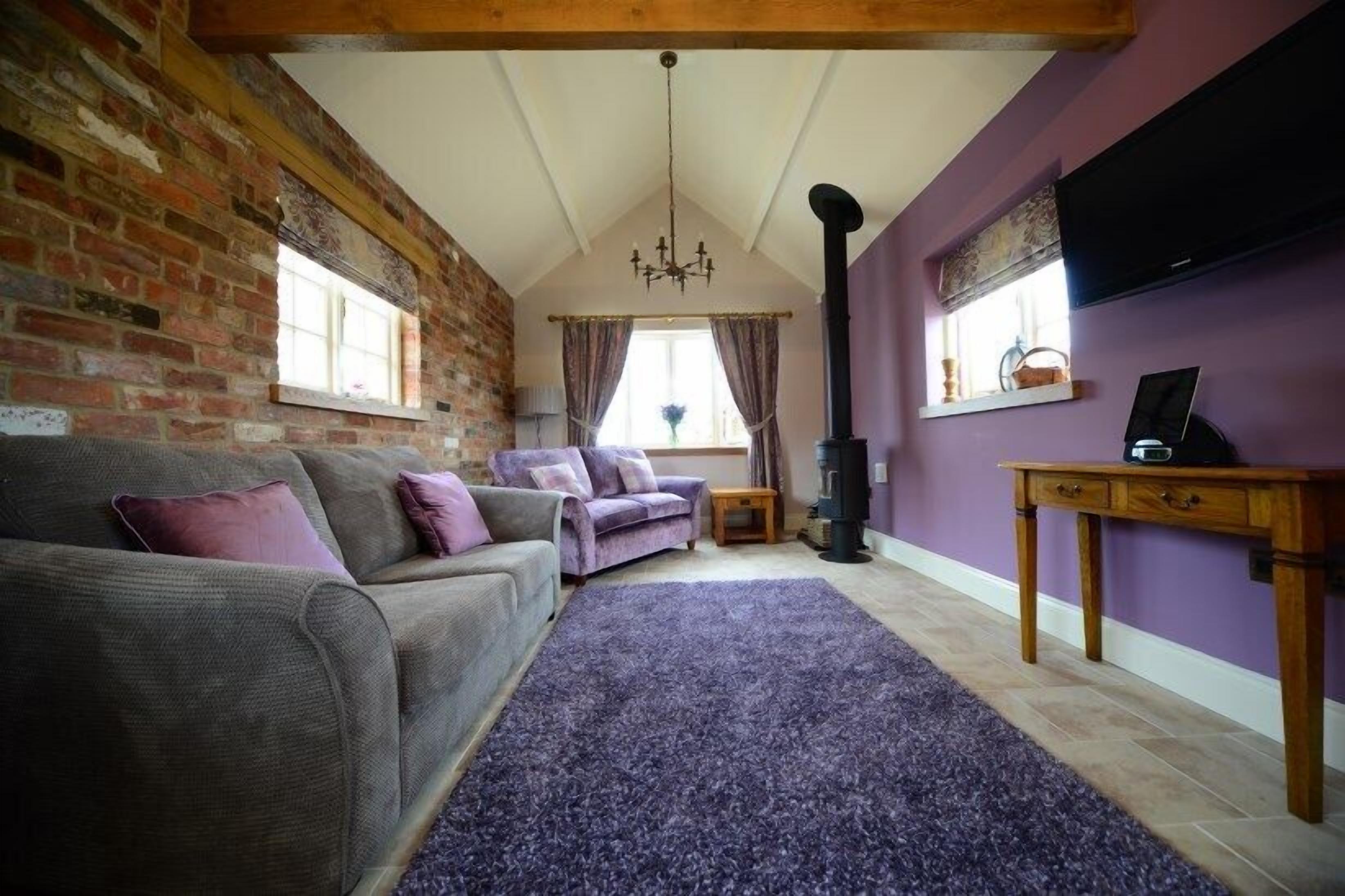Una sala de estar acogedora con pared de ladrillo, chimenea, sofá y televisor.