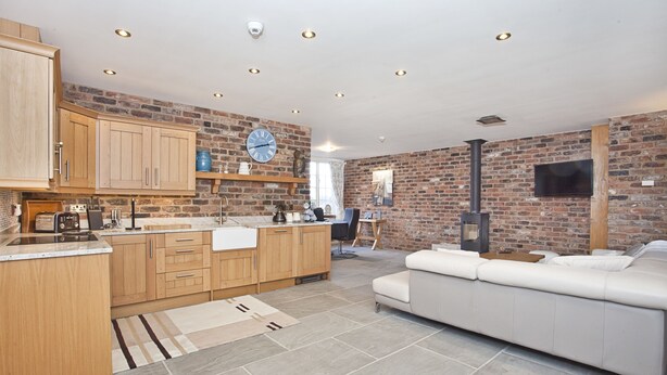 A modern kitchen with wooden cabinets, a built-in oven, and a large window. - Holtby Grange Cottages (York)