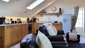 A modern kitchen with wooden cabinets, a black leather sofa, and a vintage refrigerator. - Holtby Grange Cottages (York)
