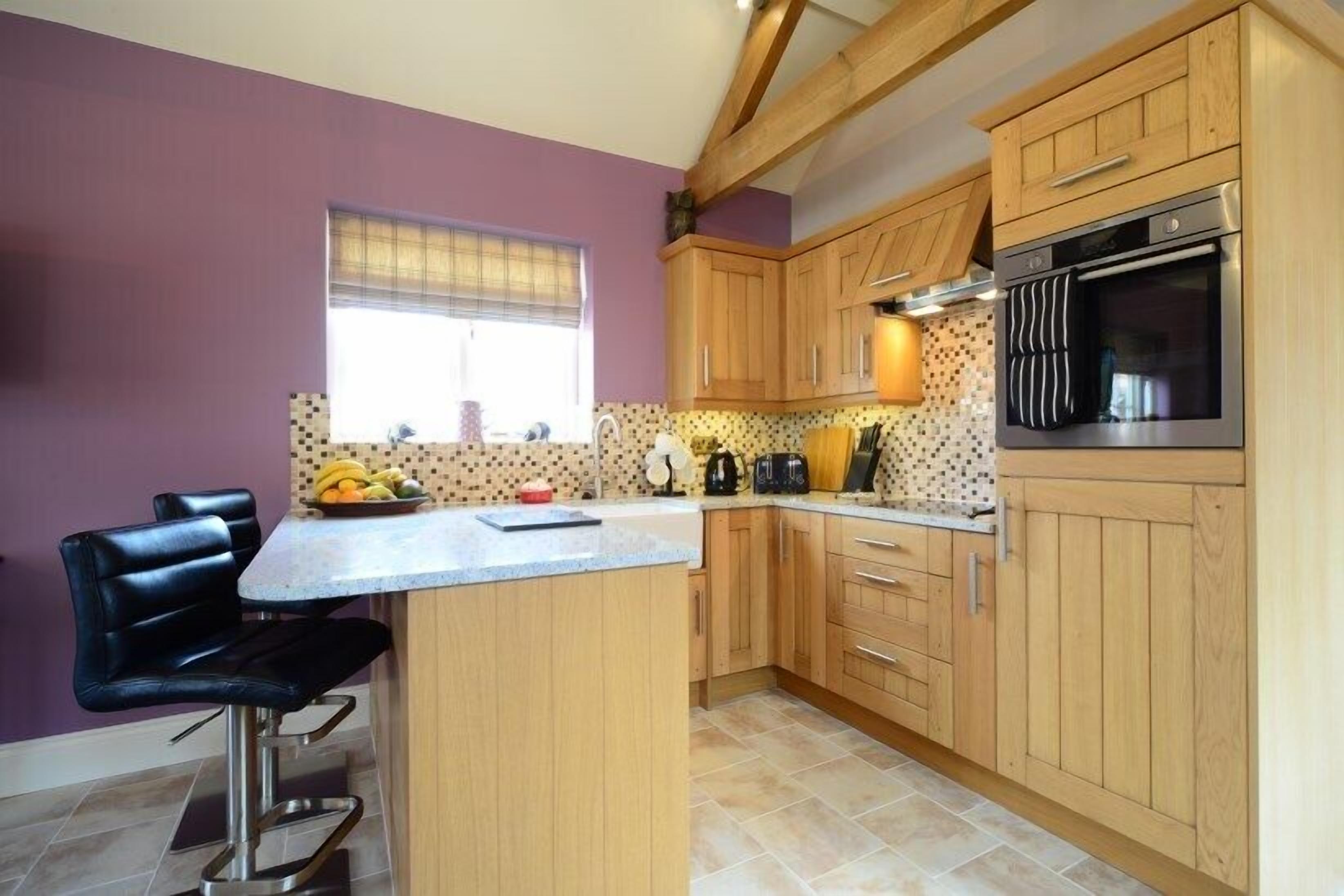 A kitchen with wooden cabinets, a built-in oven, and a bar area with stools.