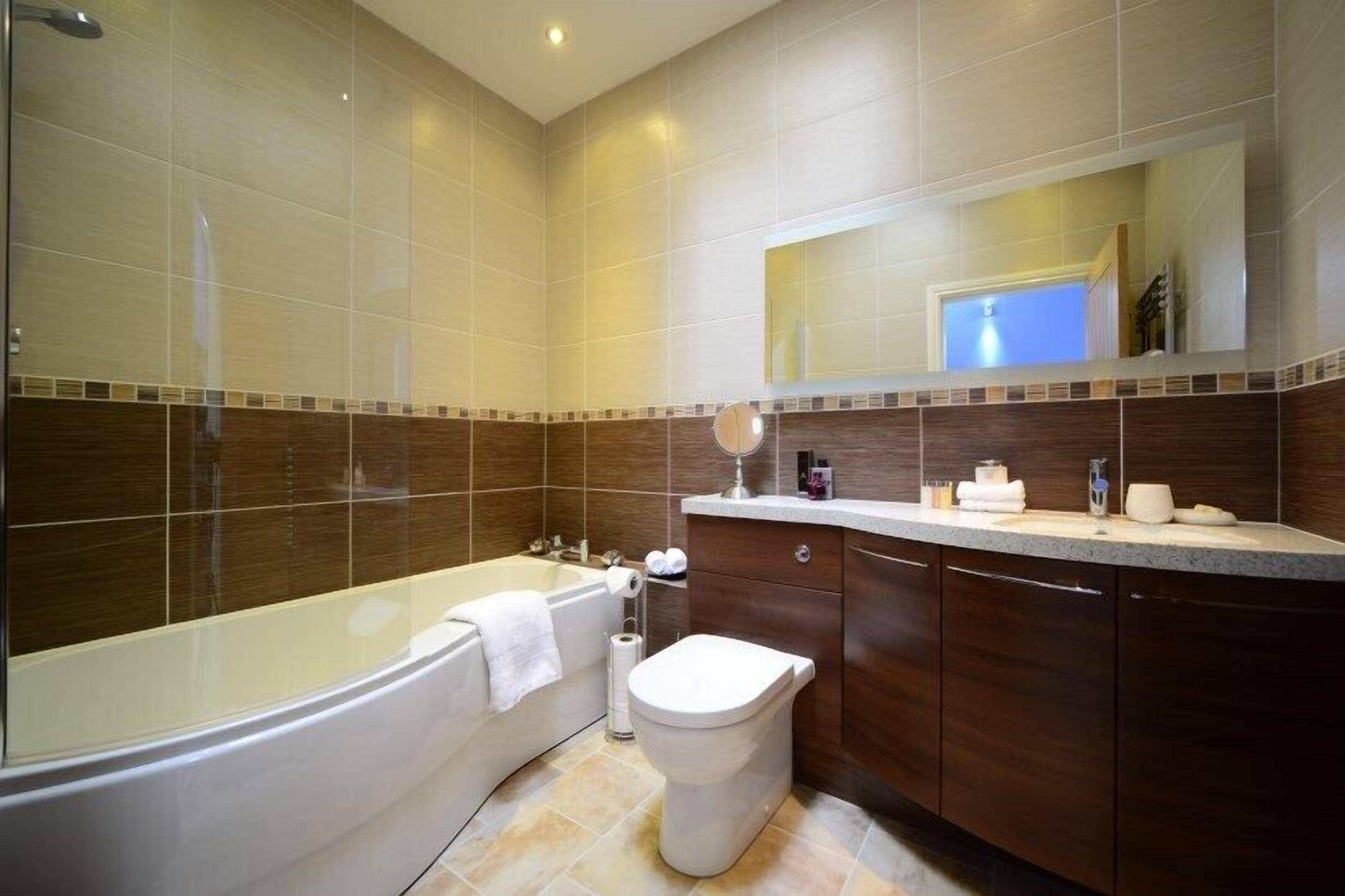 Een moderne badkamer met een bad, toilet en wastafel.