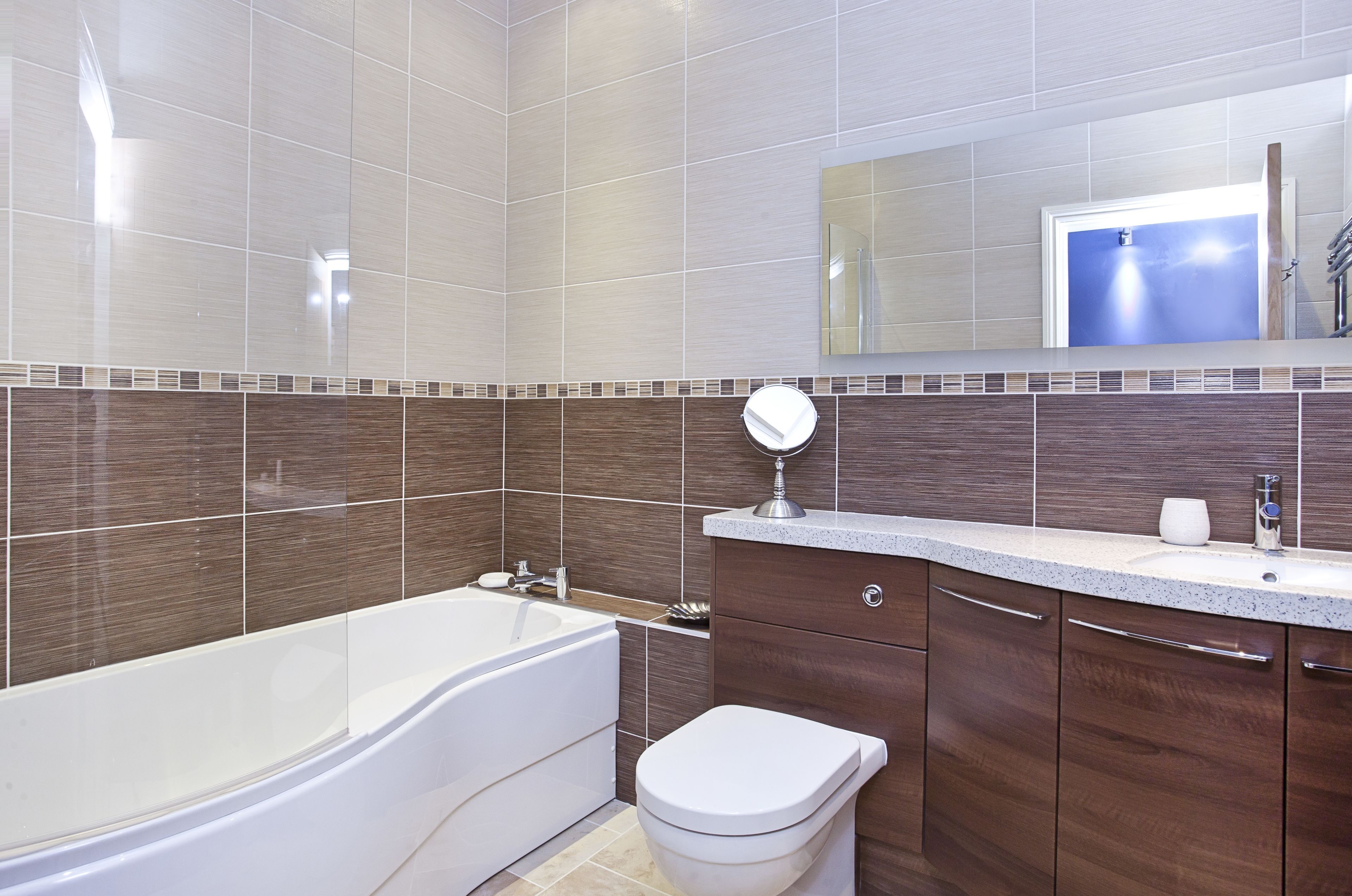 Un baño moderno con bañera, inodoro, tocador y espejo.