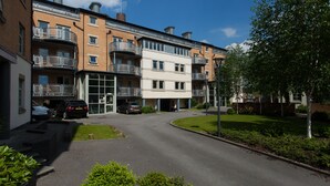 A multi-story residential building with balconies, a parking area, and a well-maintained lawn. - 20 John Walker House (York)