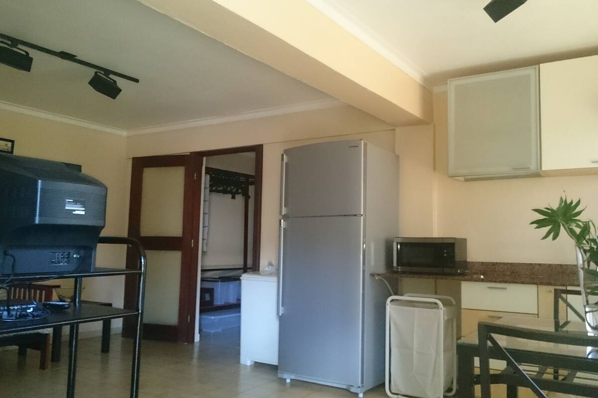 A compact kitchen with a refrigerator, microwave, and a dining area with a table and chairs.