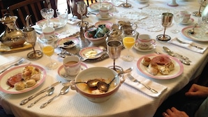 Una mesa de comedor dispuesta con platos, tazones, cubiertos y vasos, indicando un ambiente para comer.