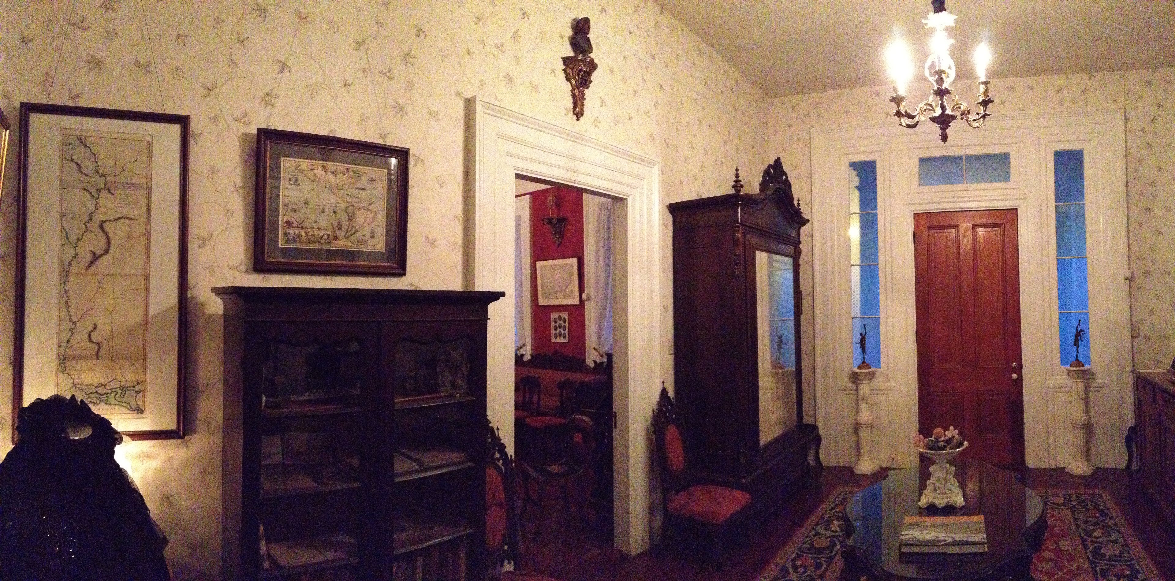Quarto com lareira, estante de livros, candelabro e porta com janelas em azul.