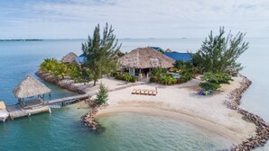 Un complexe hôtelier tropical doté de bungalows aux toits de chaume, d’une plage de sable et d’une mer d’un bleu cristallin.