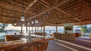 Une terrasse en bois avec un toit de chaume, un espace bar et des sièges.