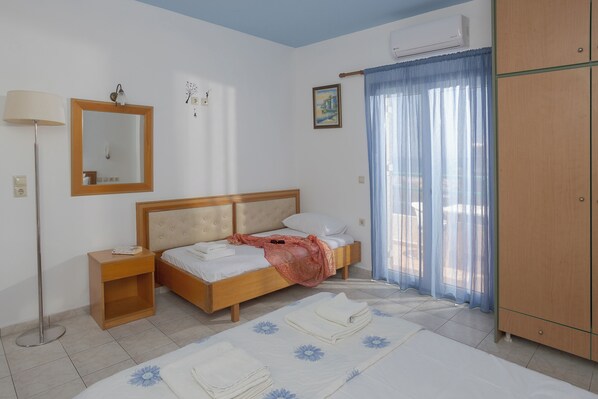 Un dormitorio con cama, mesita de noche, armario y ventana con cortinas.