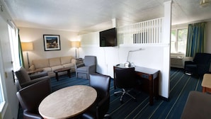 A hotel room with a sofa, armchairs, a dining table, a TV, and a desk. - Days Inn Bar Harbor (Bar Harbor)