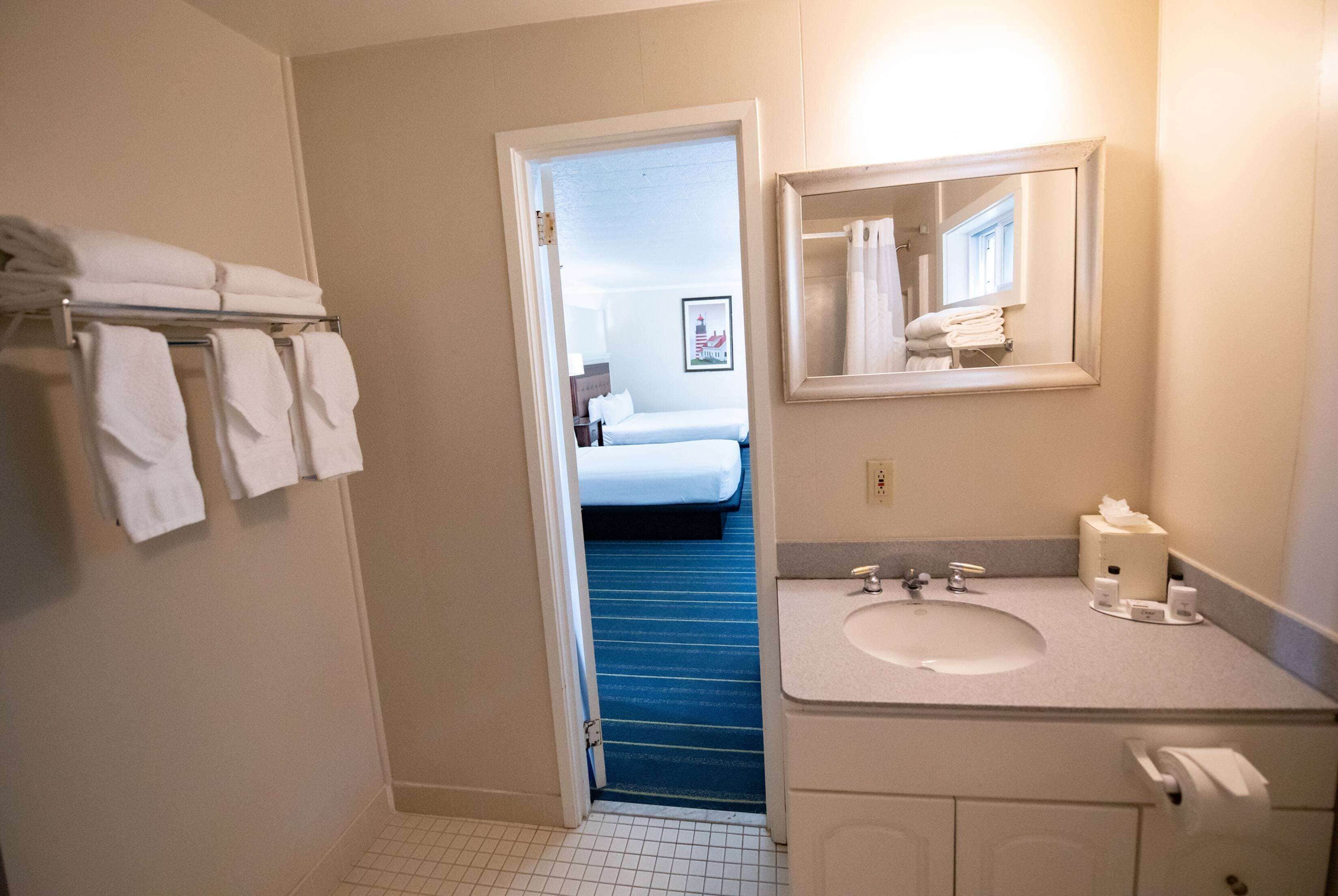 A hotel bathroom with a sink, mirror, and towels on a rack.