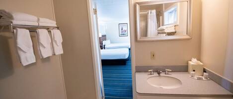 Une salle de bain d’hôtel avec un lavabo, un miroir et des serviettes rangées sur un porte-serviettes.