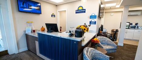 A reception area with a blue counter, a television mounted on the wall, and a sign for Days Inn by Wyndham.