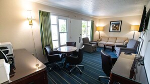 A hotel room with a dining table, chairs, a sofa, a TV, and a window with curtains. - Days Inn Bar Harbor (Bar Harbor)