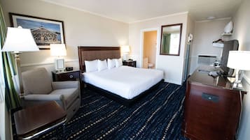 Quarto de hotel com uma cama grande, uma cadeira, uma escrivaninha e uma cômoda.