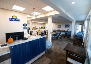 A reception area with a blue counter, a television, and a pumpkin decoration. There are dining tables and chairs in the background.