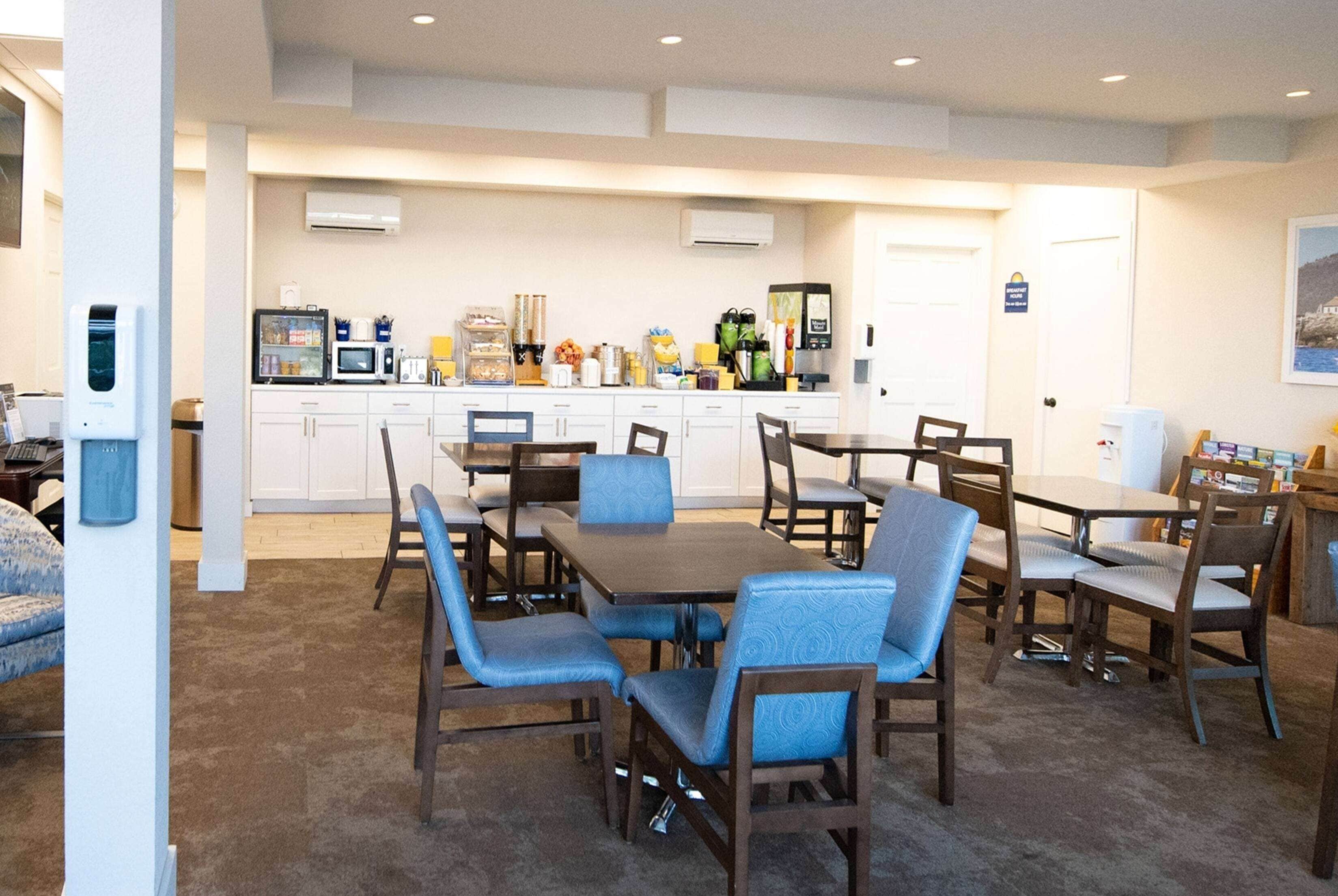 A dining area with a round table and chairs, a kitchen in the background, and a white door with a sign.