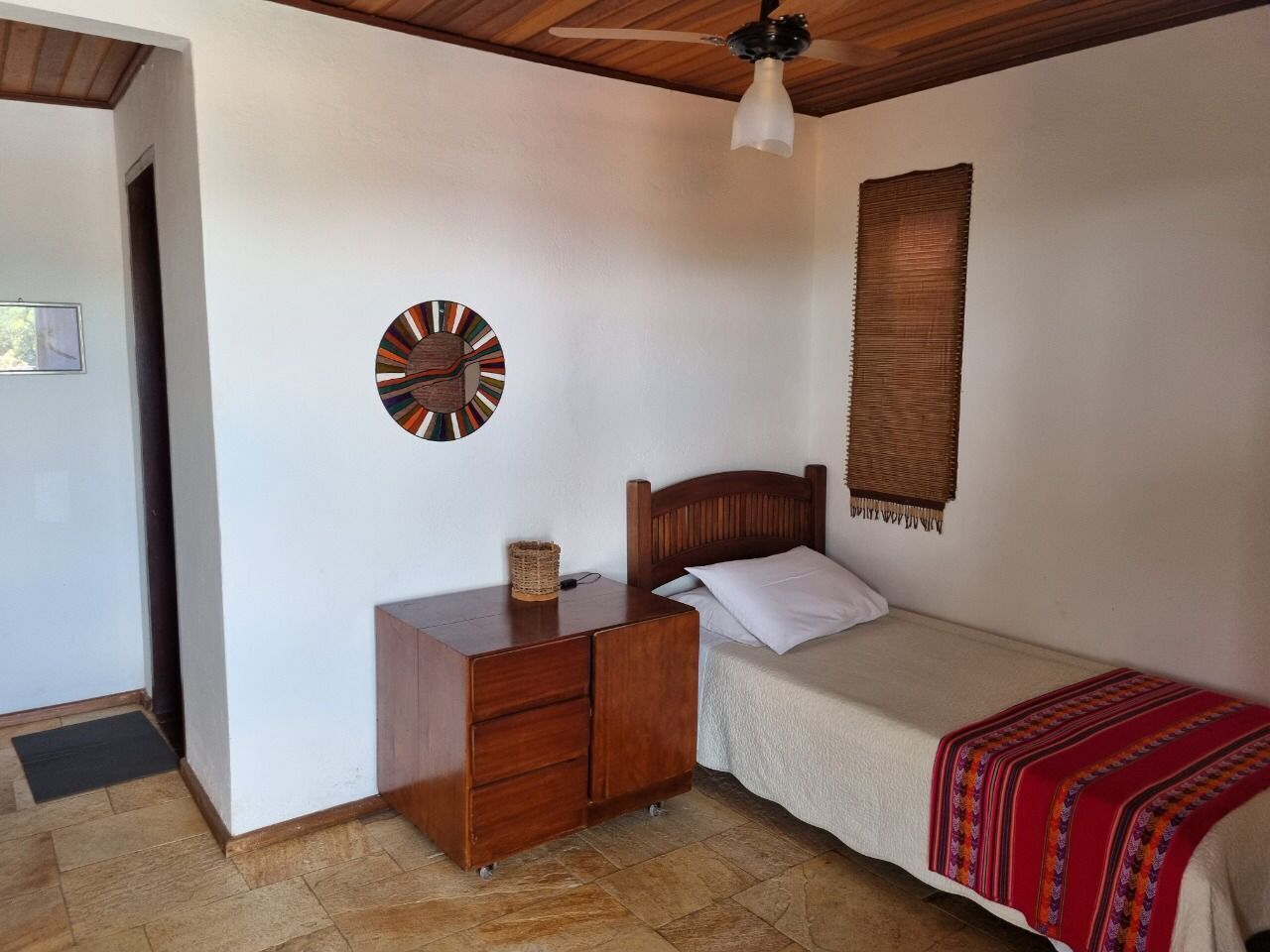 Une chambre à coucher avec un lit en bois, une table de chevet, une horloge murale et une décoration murale tissée.