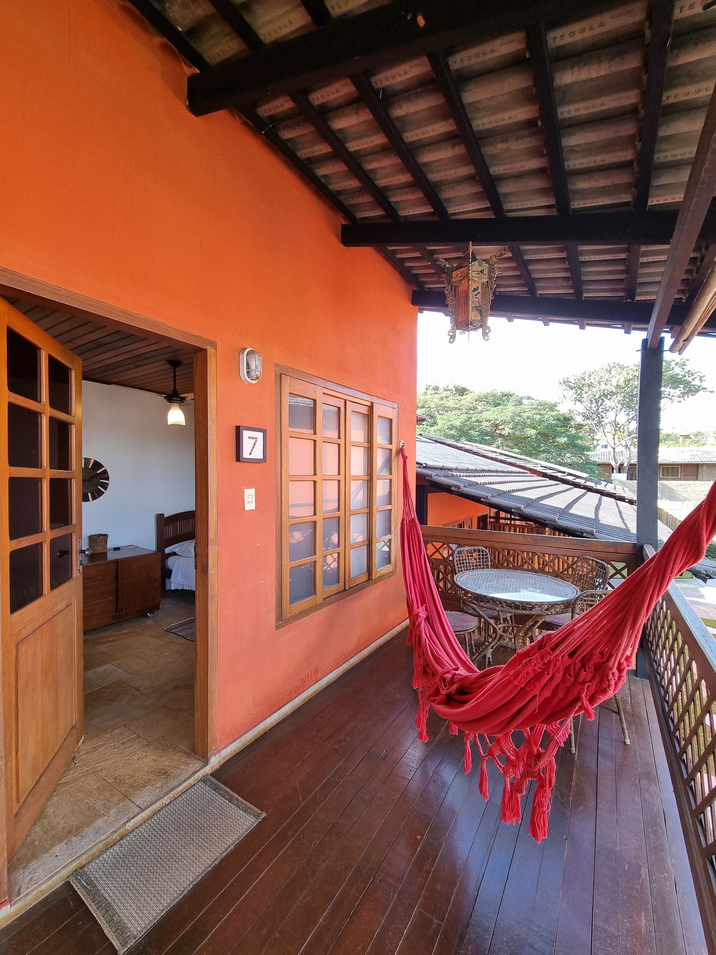 A wooden deck with a hammock, a wooden door, and a window with frosted glass.