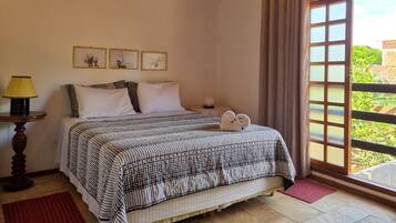 A bedroom with a bed, a nightstand, a lamp, and a window with curtains.