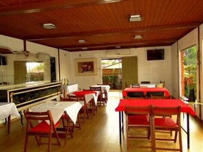 A restaurant with wooden ceiling and tables covered with red tablecloths. - Pousada Ikabana (Pirenópolis)