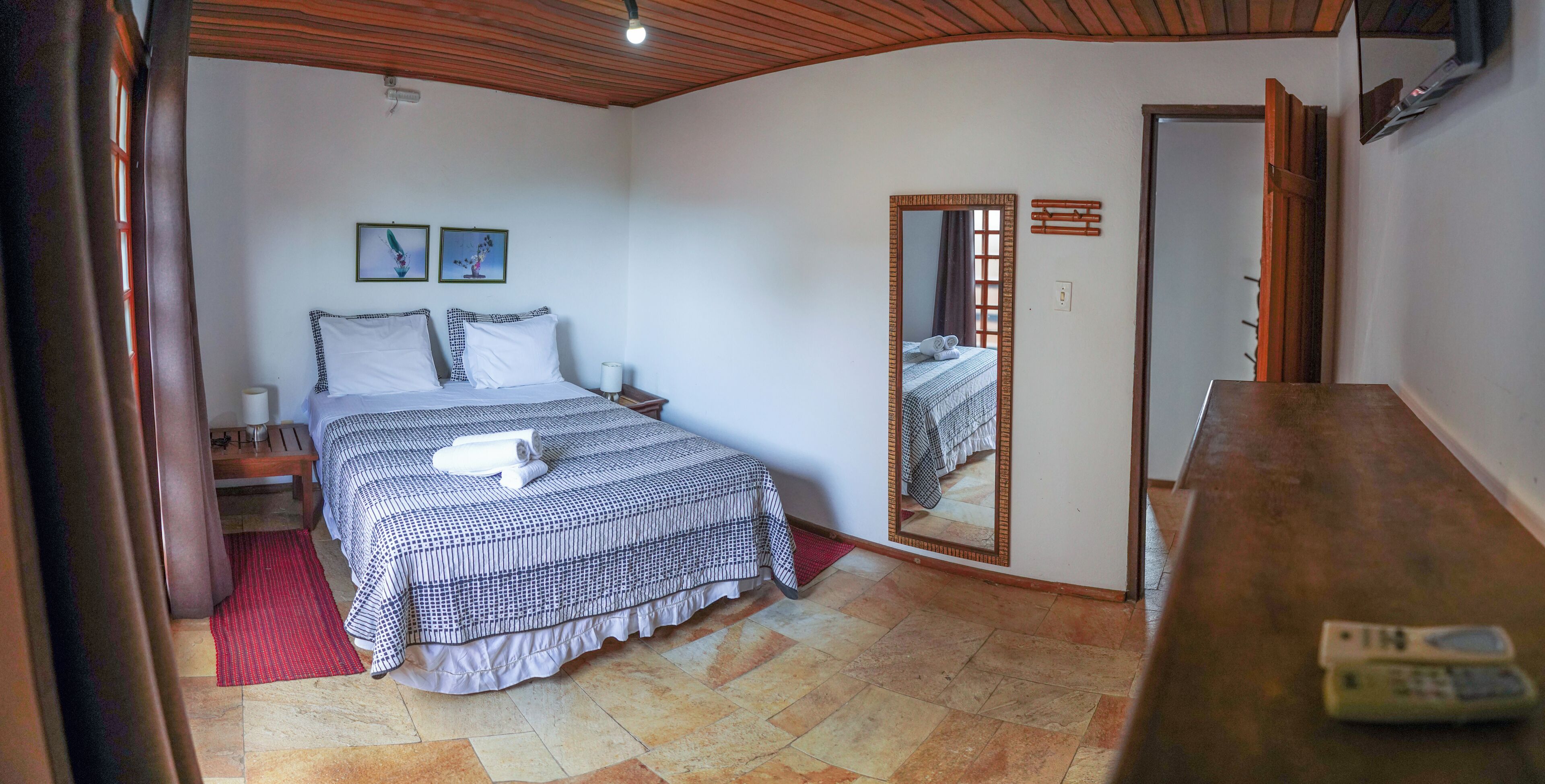 A bedroom with a bed, a bedside table, a mirror, and a wooden headboard.