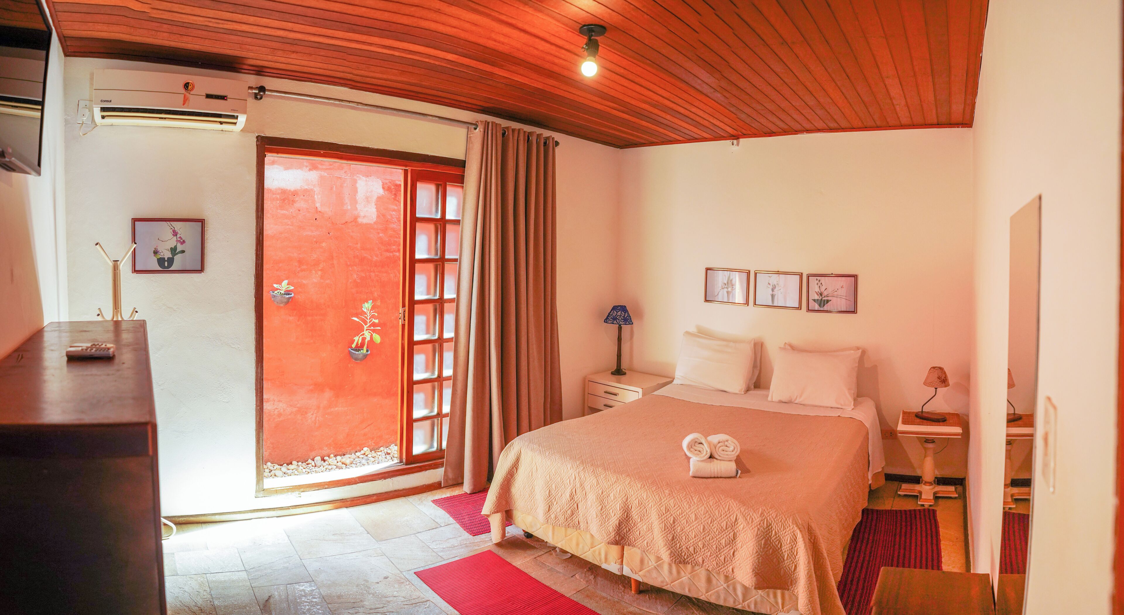 A hotel room with a bed, bedside table, lamp, and a door leading to a balcony.
