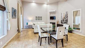 Un amplio salón con una mesa de comedor, sofás blancos y un televisor.