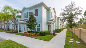 A two-story residential building with a light blue exterior, a front porch, and a well-maintained lawn. - Modern,Stylish & Minutes from Disney (kissimmee)