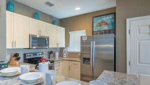 A kitchen with white cabinets, a stainless steel refrigerator, a microwave, and a granite countertop. - Modern,Stylish & Minutes from Disney (kissimmee)