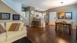A modern kitchen with a microwave, refrigerator, and dining area with a table and chairs. - Modern,Stylish & Minutes from Disney (kissimmee)