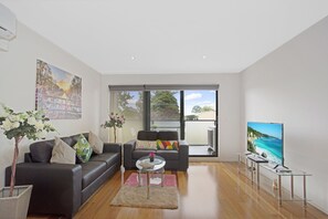 Una sala moderna con sofá, mesa de centro y televisor que muestra un paisaje.