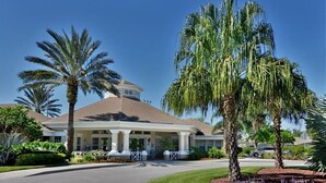 A hotel with a central dome structure, palm trees, and a well-maintained lawn. - Orlando Oasis (Kissimmee)