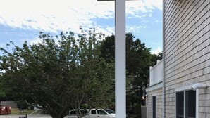 A residential property with a paved patio, a lawn with stepping stones, a tree, and a driveway with parked vehicles. - Beautiful Provincetown 2 bedroom  centrally located (Provincetown)