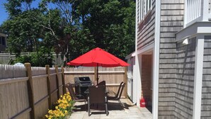 A patio with a barbecue area, outdoor furniture, and yellow flowers. - Beautiful Provincetown 2 bedroom  centrally located (Provincetown)