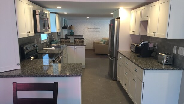 A modern kitchen with white cabinets, granite countertops, stainless steel appliances, and a central island. - Beautiful Provincetown 2 bedroom  centrally located (Provincetown)