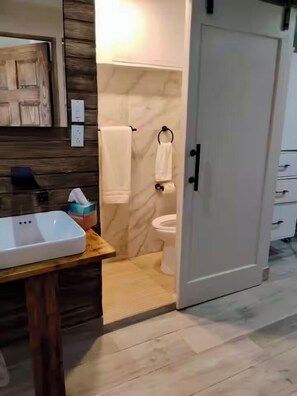 A bathroom with a toilet, a sink, and a mirror. - Segovia Studio Units (Carolina)