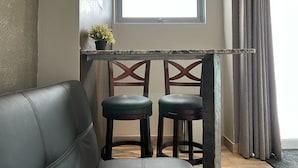 A small kitchenette with a window, two stools, and a potted plant. - Segovia Studio Units (Carolina)