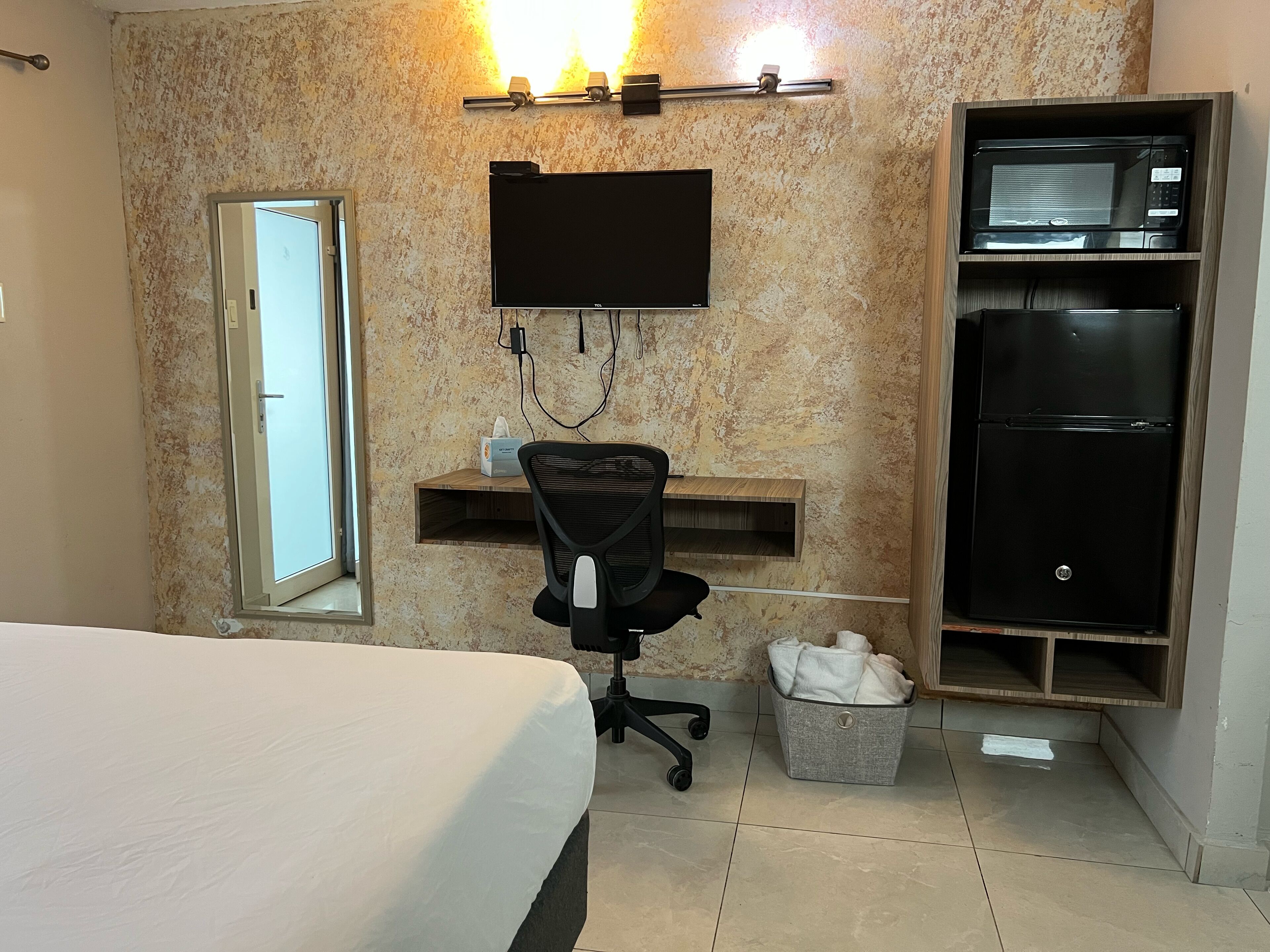 Une chambre d’hôtel comprenant un lit, un bureau avec une chaise, un téléviseur fixé au mur, un four à micro-ondes et un réfrigérateur.