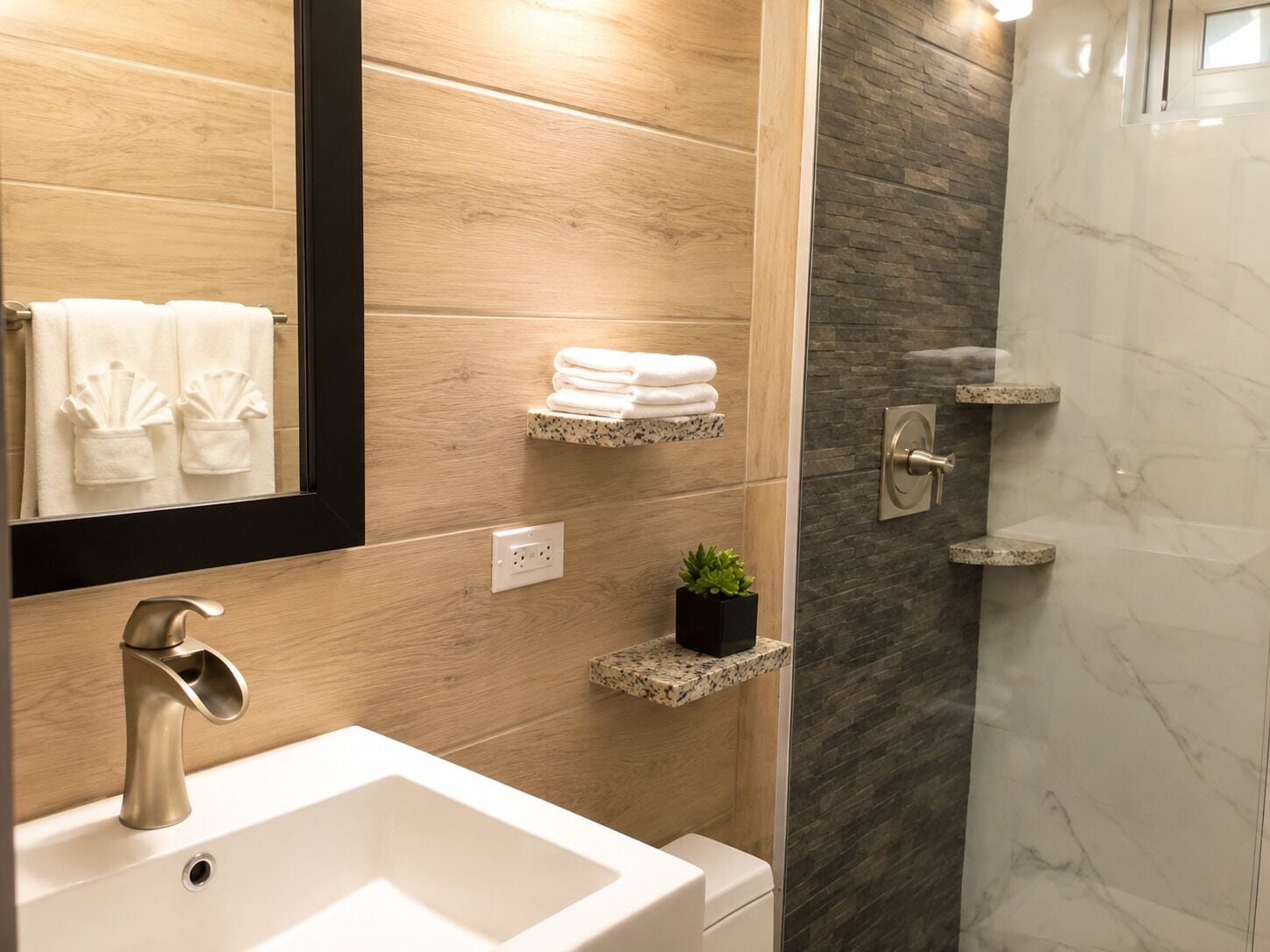 A modern bathroom with a white sink, a mirror, and a shower area.